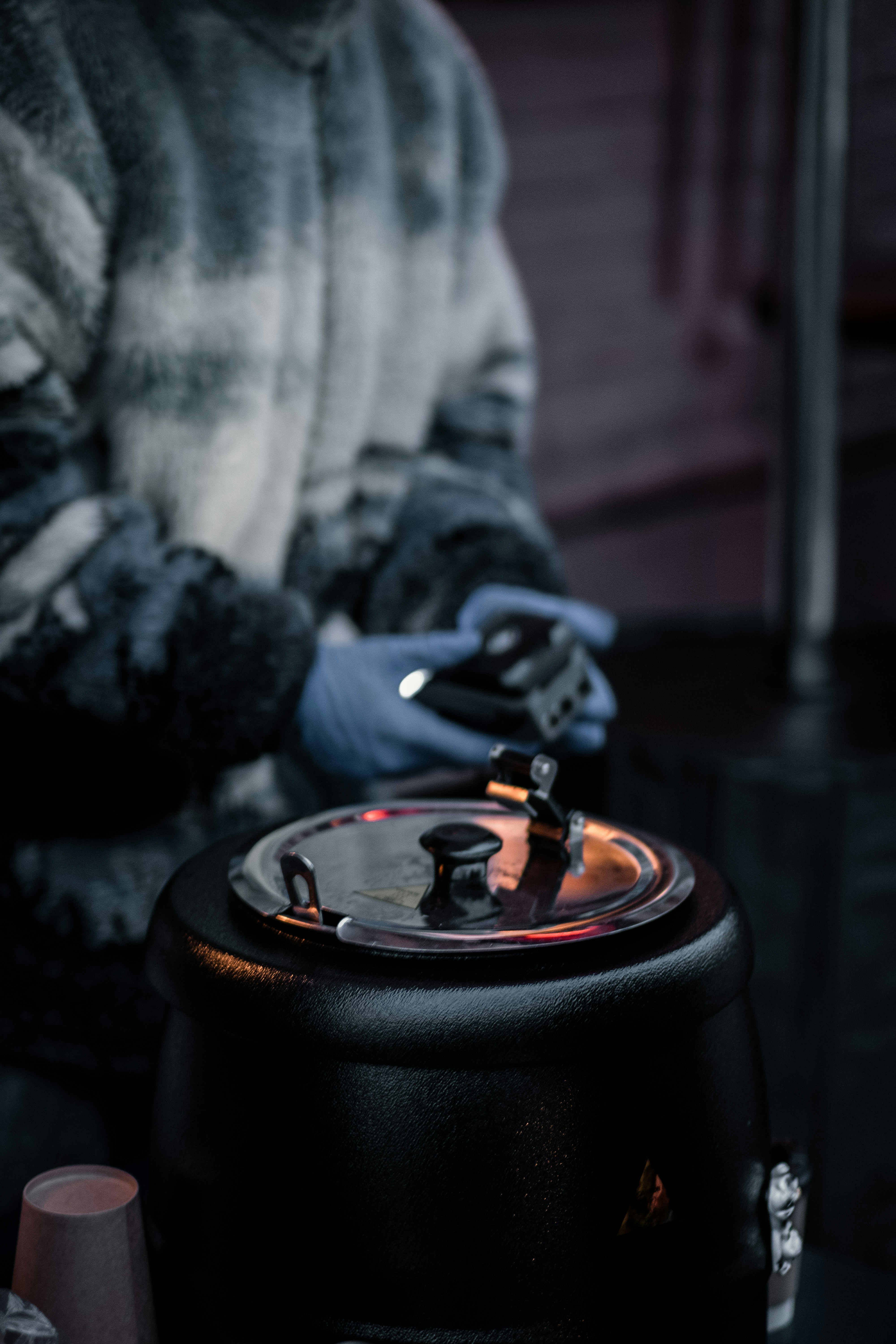 person in gray jacket holding black round metal